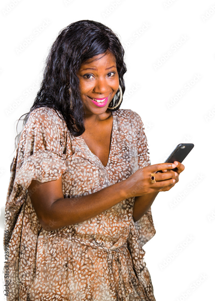 lifestyle portrait of young beautiful and happy black African American woman in sweet dress smiling cheerful using internet app on mobile phone or texting excited isolated