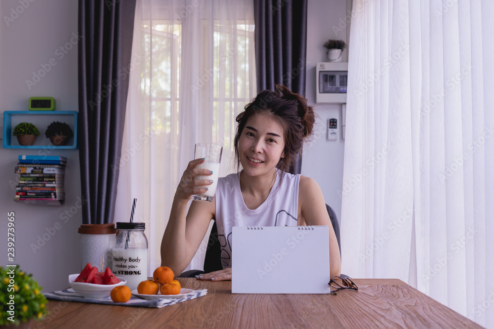 breakfast table with young asian woman drink some milk in living room.