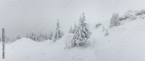 Panorama of heavy snow on top of the mountain. Cold winter day with heavy fog and snow