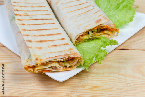 Shawarma wrapped inside of flatbread on white dish close-up photo