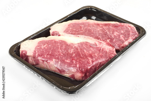 Raw steak in an airtight vacuum package on a white background.