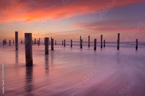 Wooden poles on the beach at sunset