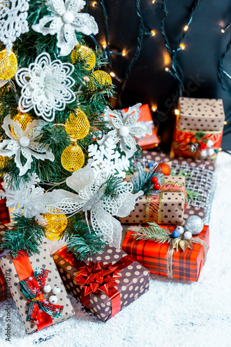 Christmas gifts in the snow under the tree. The concept of home holiday, surprises and present
