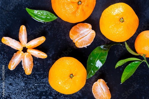 Beautiful ripe tangerines with leaves and water drops on a dark background.