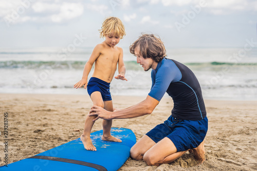 Photography Father or instructor teaching his 4 year old son how to surf in the sea on vacation or holiday