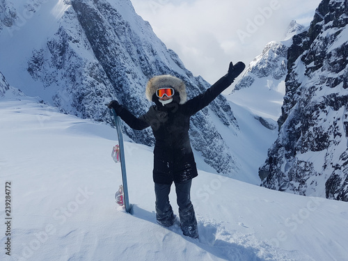 Cheerful snowboarder outstretches her arms before riding down untouched hill. photo