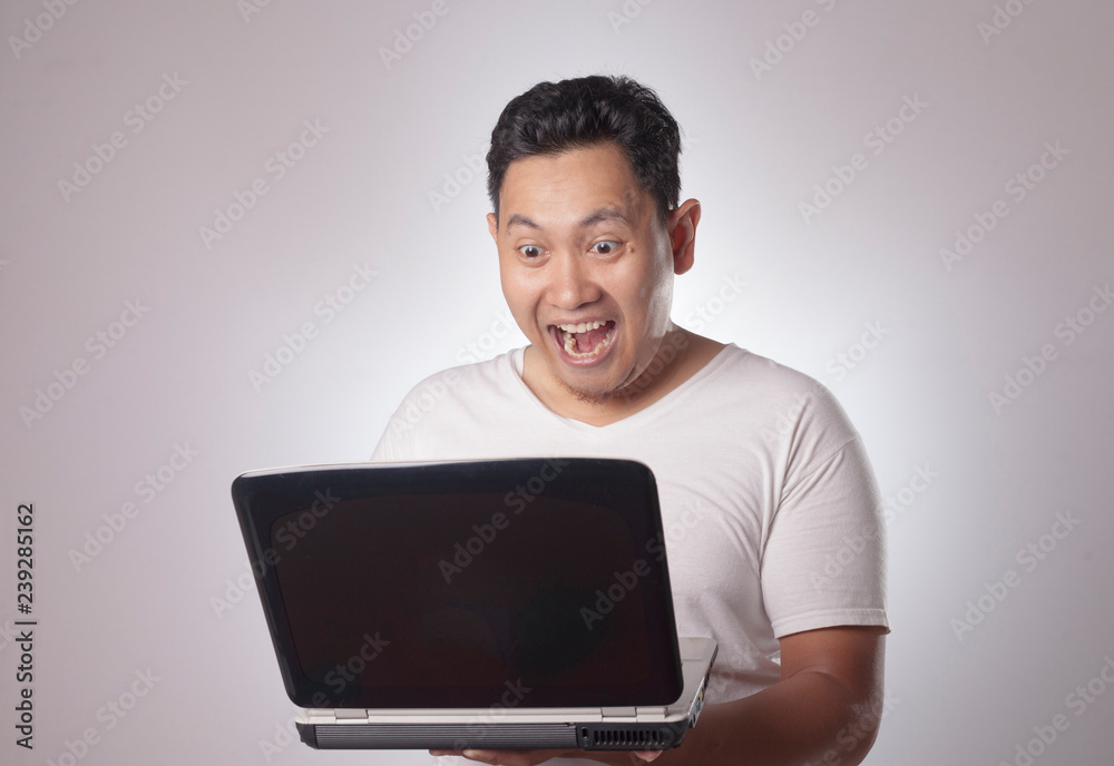 Young Man Looking at Laptop, Surprised Expression Young Man Looking at Laptop, Surprised Expression