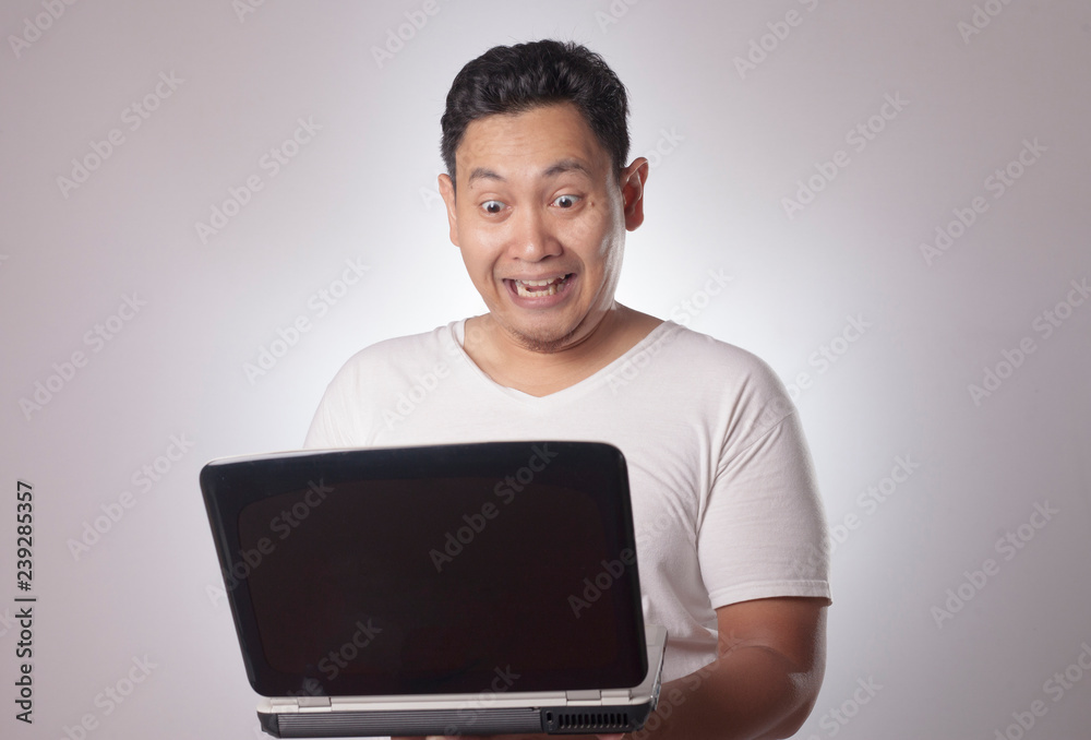 Young Man Looking at Laptop, Surprised Expression Young Man Looking at Laptop, Surprised Expression