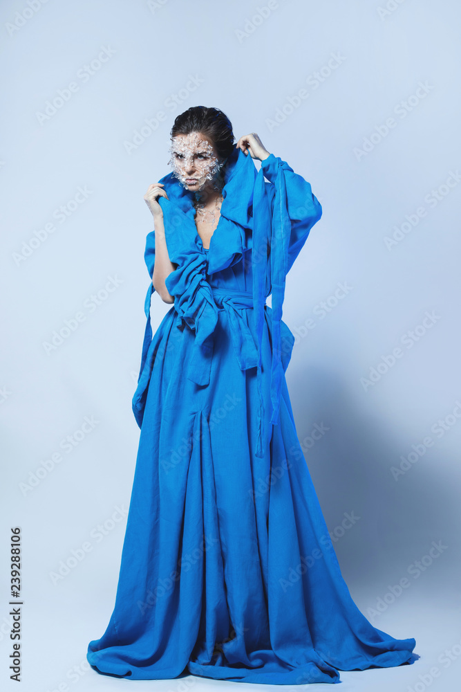 Naklejka premium Woman with a pieces of glass or ice on her face, wearing beautiful blue dress