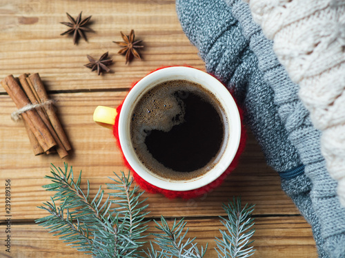 hot coffee and cozy home background. warm knitted sweaters, Christmas tree branches and cinnamon sticks