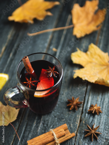 Mulled wine on a dark wooden table with cinnamon, anise and autumn dry leaves