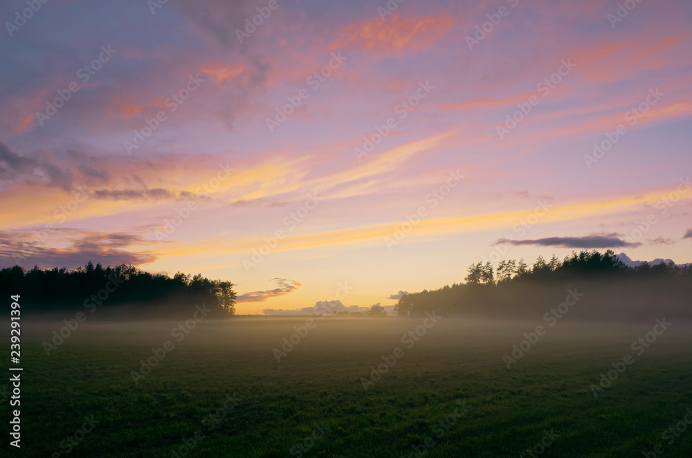 Colorful sunset on mist-covered fields.
