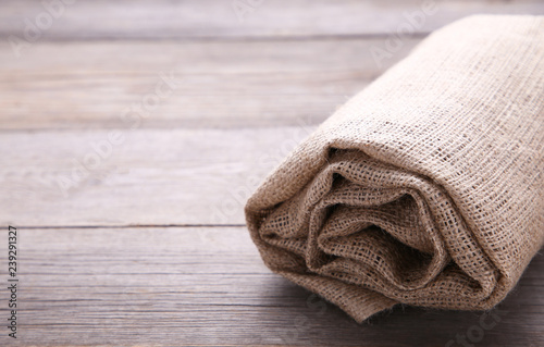 Rolled up sackcloth on grey wooden background