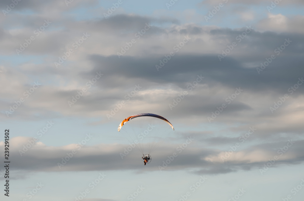 A hang glider in flight with nice clouds.