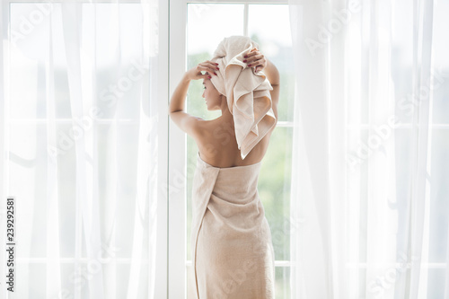 Young attractive woman after bathing. Female in towels. Beautiful lady moisturizing her body with body lotion. Portrait of young girl in the bethroom photo