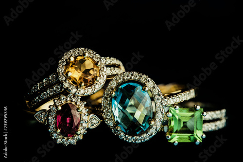 Four shiny golder rings with precious gems isolated on black.