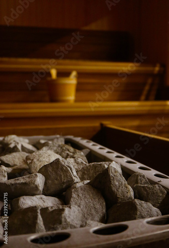 Wooden Bathhouse with a heating pot filled with stones, close up. Wooden sauna interior with equipment, coals, ladle, bucket.