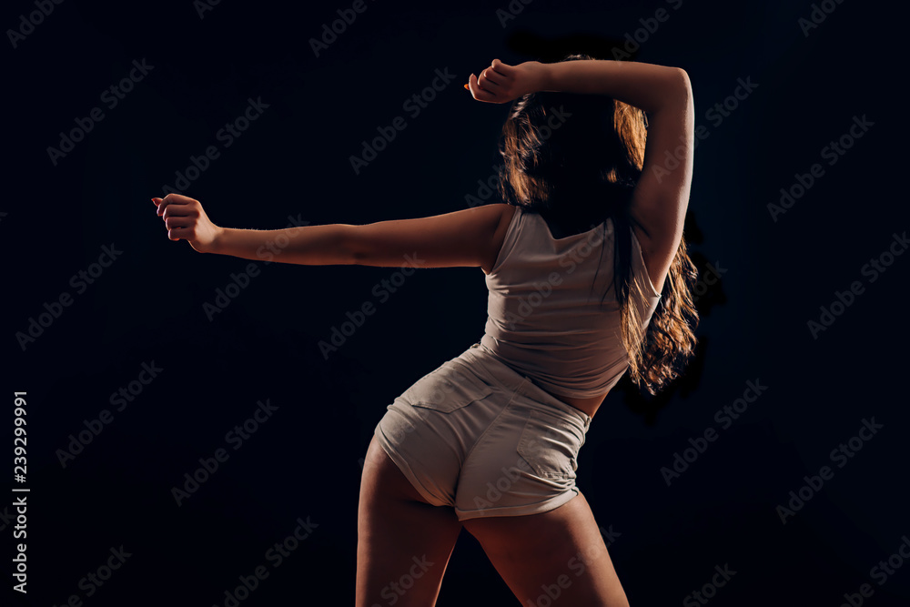 Sexy slim tanned woman dancing twerk on black background from behind Stock  Photo | Adobe Stock