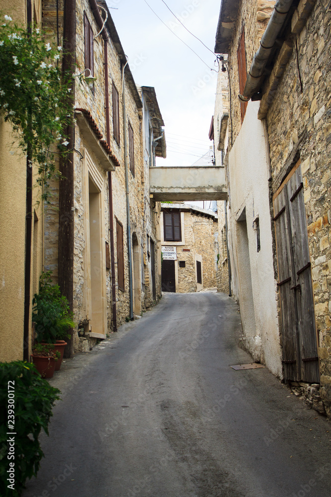 Obraz premium Długie wąskie uliczki składające się ze starych kamiennych domów zbudowanych w jednej linii w wiosce w górach na Cyprze