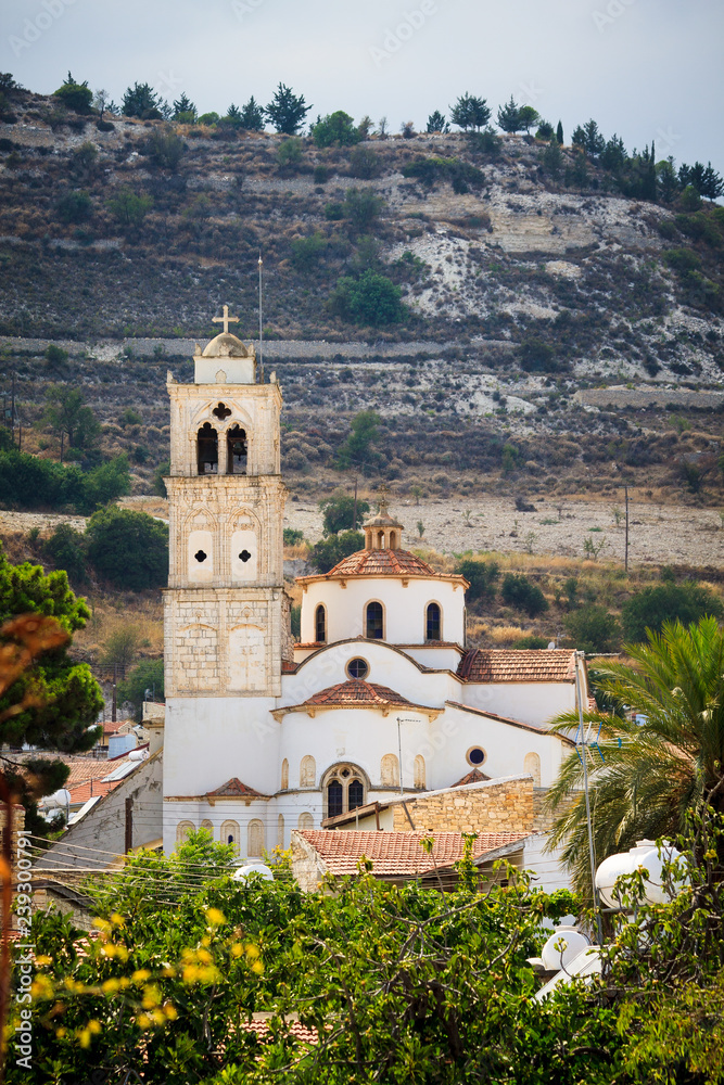 A large white the holy cross church with a red tile roof and a tower with a bell tower in the Lefkara village mountains Troodos on the island of Cyprus