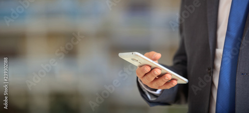 Man holding phone. Young businessman in business wear using a mobile, closeup view on smartphone, banner