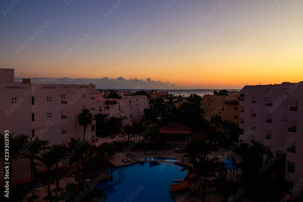 View of the luxurious hotel with a swimming pool and Red sea at sunrise