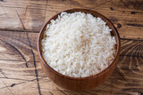 White rice grits in wooden bowl on rustic wooden background.