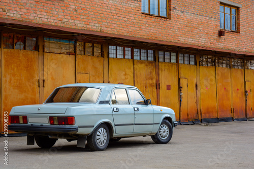 Photo of old car standing before rusty gate of building © Badunchik