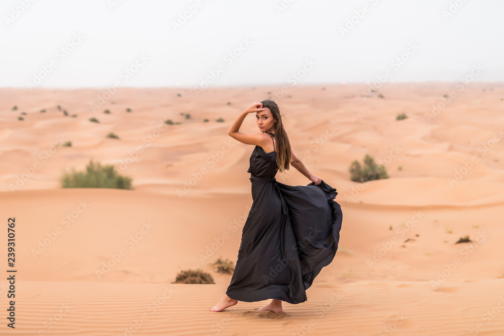 Beautiful pretty woman in black dress on a sand dune of desert Stock Photo  | Adobe Stock