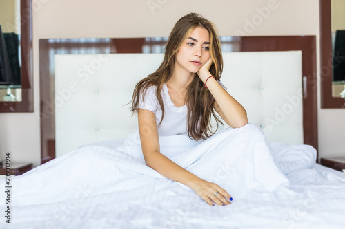Canvas Print Sad young woman sitting on the bed at the morning