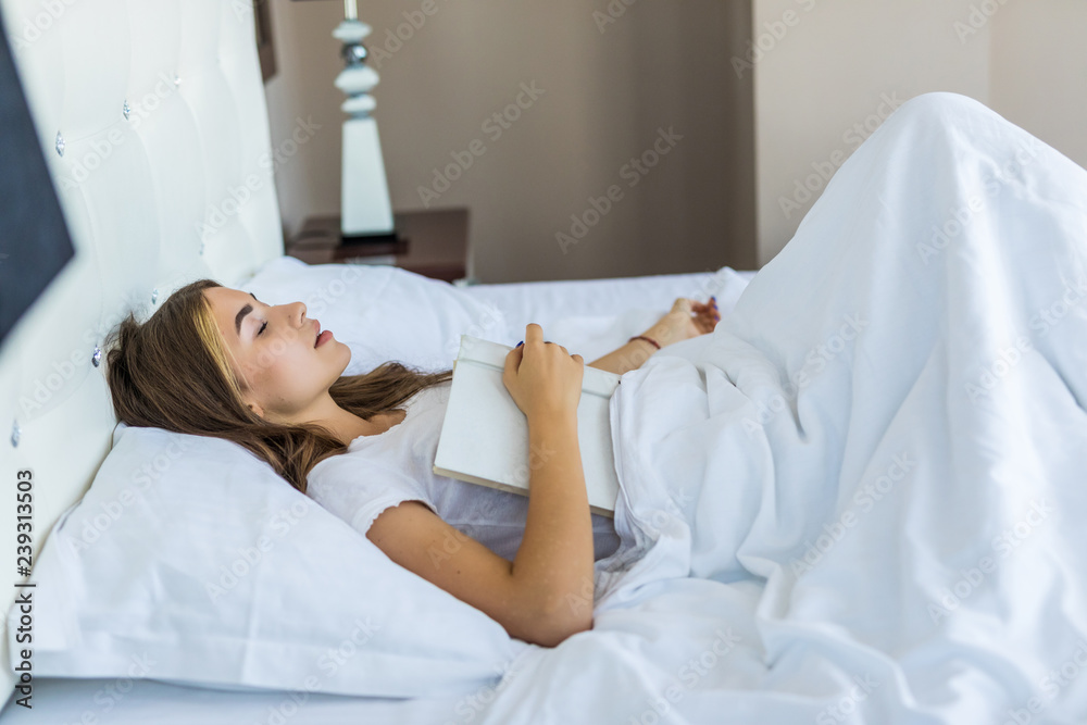 Top view of beautiful peaceful young woman holding book and sleeping in bed Top view of beautiful peaceful young woman holding book and sleeping in bed