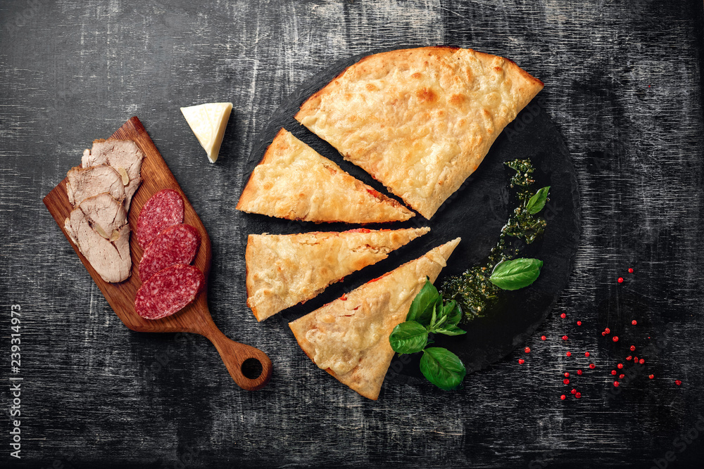 Traditional Italian pizza calzone with ingredients on a stone and dark ...