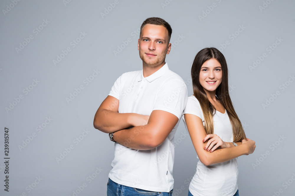 Portrait of couple standing back to back and looking at camera over gray wall Portrait of couple standing back to back and looking at camera over gray wall