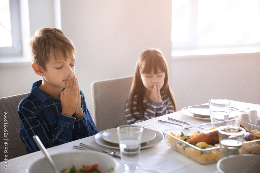 Cute children praying before meal at home Cute children praying before meal at home