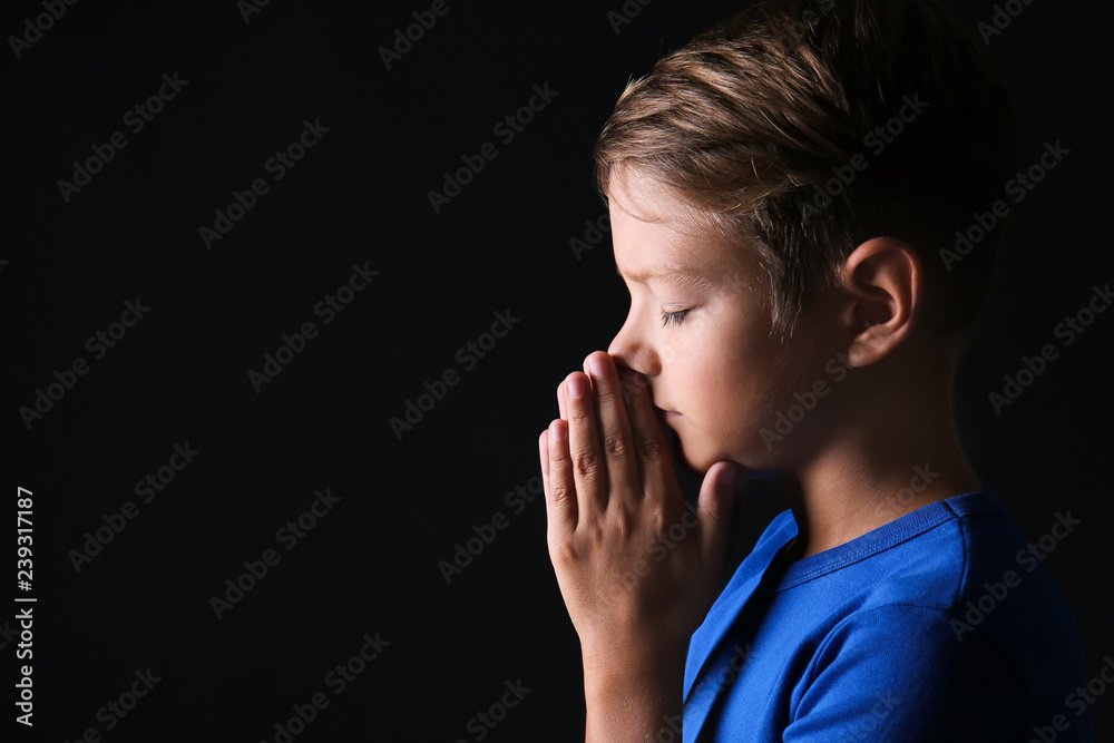 Portrait of praying boy on dark background Portrait of praying boy on dark background