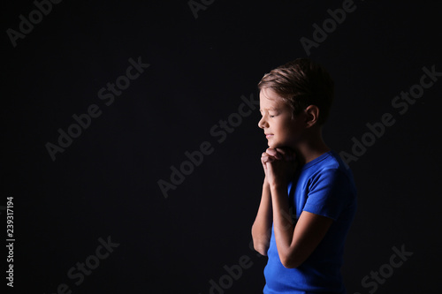 Portrait of praying boy on dark background © Pixel-Shot