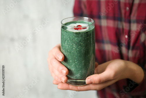 Woman with glass of spirulina smoothie, closeup