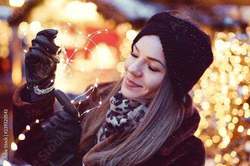 Young imaginative woman holding fairy lights in Christmas market