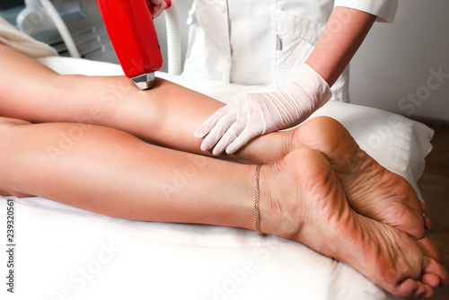 Beautiful woman legs on laser hair removal at epilation cabinet and master of hair removal