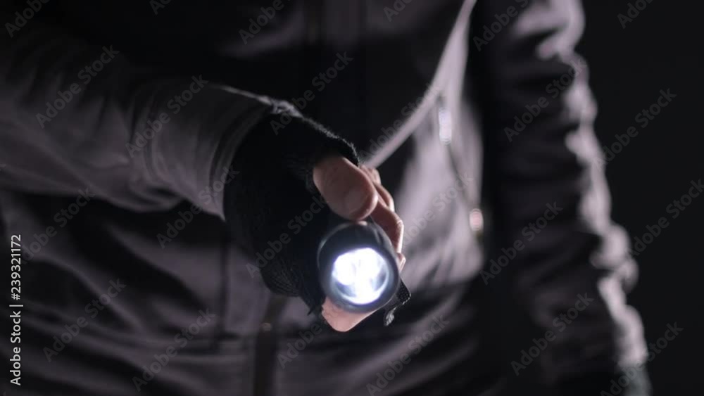 Burglar intruder with flashlight torch at night, low key selective focus