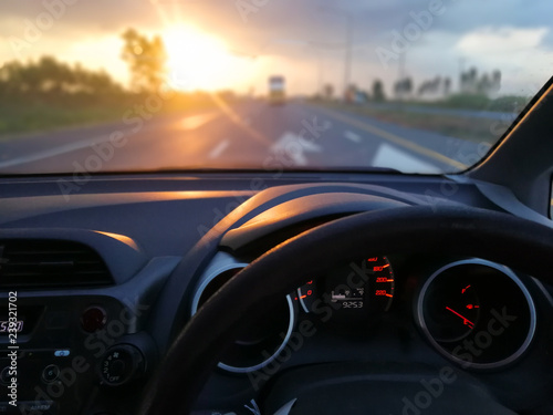 steering wheel and View on the dashboard of car driving on the road at sunset in front of the car.