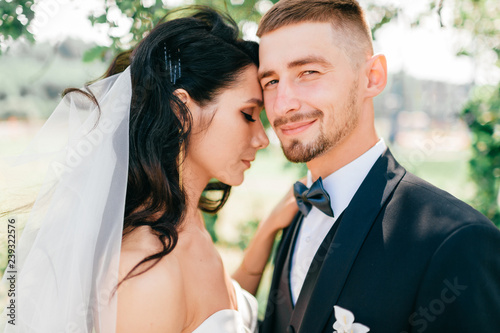 Beautiful wedding couple outdoor portrait. Young pretty bride hugging groom at nature. Fine art lifestyle portrait of loving pair. Wedding photosession. Second half. Just married. Happy bridal day.