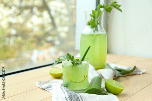 Glass and jug of aloe vera cocktail on wooden windowsill