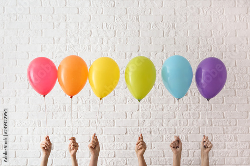 Women holding rainbow air balloons on light background. LGBT concept photo