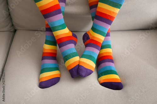 Legs of lesbian couple in rainbow stockings on sofa at home