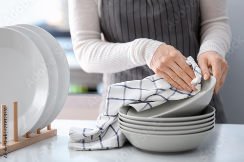 Obraz na płótnie Woman wiping plate with towel in kitchen