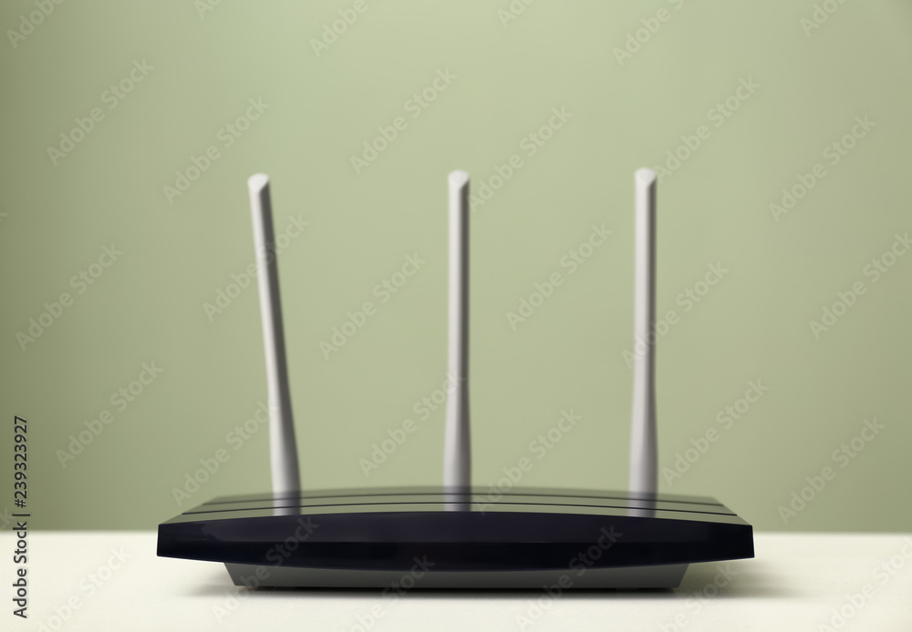 Modern wi-fi router on light table against color background Modern wi-fi router on light table against color background