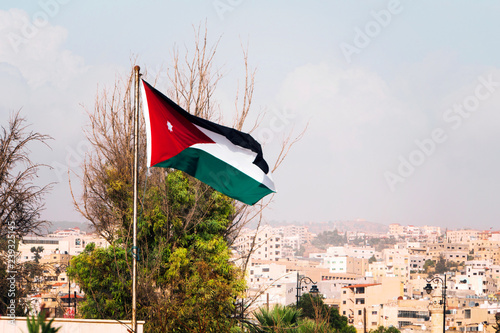 tricolor flag of Jordan on the background of the old poor of the city and blue sky. photo