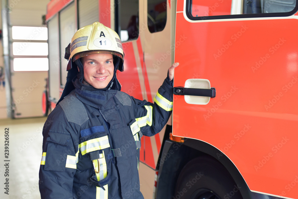 Obraz premium portrait of a firefighter at the emergency vehicle in the fire station