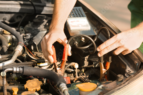 Male mechanic charging a car battery